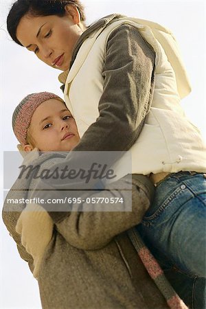 Little girl embracing mother, low angle view