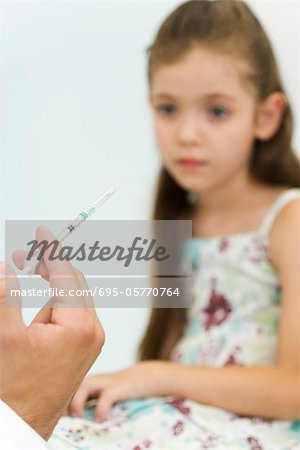 Doctor holding syringe, preparing to vaccinate little girl, cropped