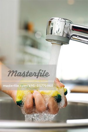 https://image1.masterfile.com/getImage/695-05770960em-person-rinsing-sponge-under-kitchen-faucet-stock-photo.jpg