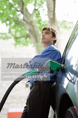 Well-dressed man refueling vehicle at gas station