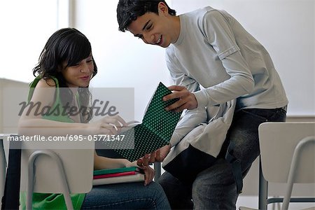 High school student showing book to classmate