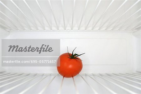 Single red tomato sitting on shelf inside refrigerator