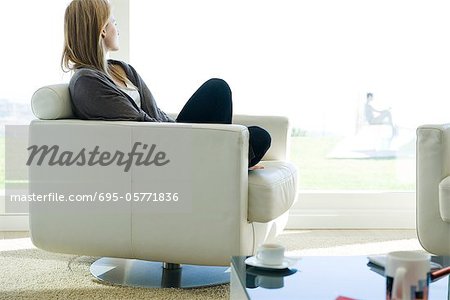 Woman relaxing in armchair, gazing out window