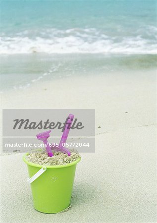 Bucket filled with sand and beach toys on beach