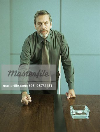 Businessman pounding fist on table, portrait