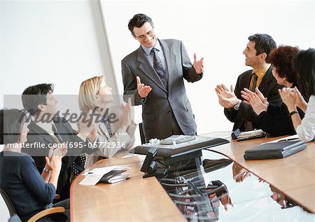 Business people in conference room, applauding standing businessman