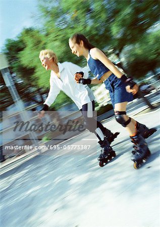 Mature woman and girl in-line skating, blurred