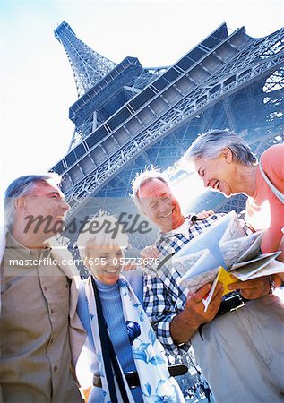 France, Paris, mature tourists examining a map in front of Eiffel Tower, low angle view
