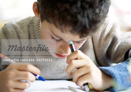 Boy bending head over notebook, writing, close-up