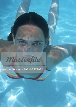 Close-up of teenage girl swimming underwater,bubbles coming out of nose