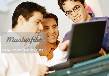 Three men looking at laptop computer