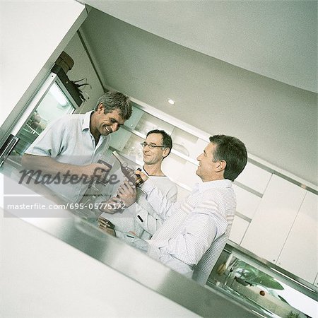 Three men having a drink in kitchen