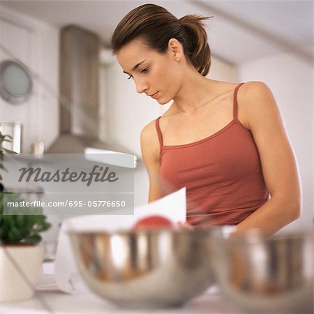 Woman working in kitchen, waist up, bowls on counter in foreground, blurred