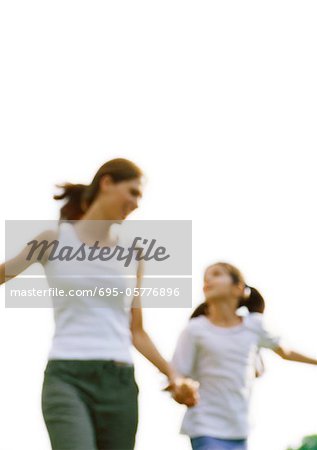 Woman and girl looking at each other and holding hands, blurred motion, low angle view