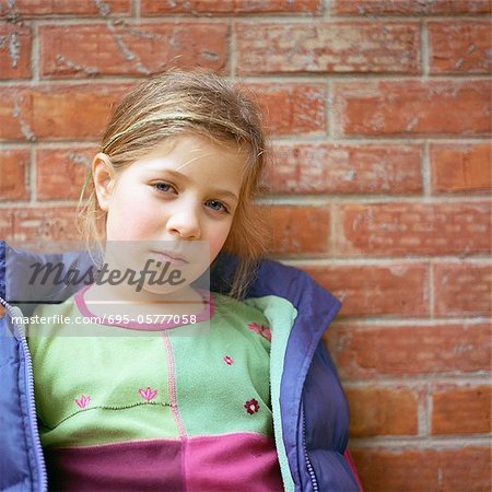 Girl leaning against brick wall, portrait