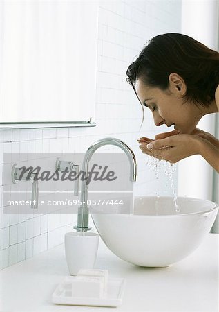 Woman Bending Over Sink Washing Face Stock Photo