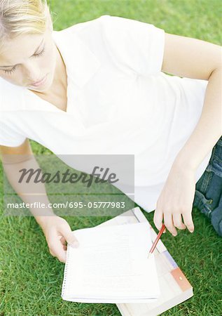 Female student reclining on grass, studying