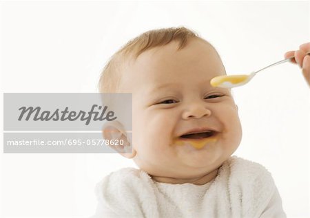 Smiling baby being fed baby food