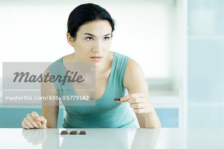 Woman eating chunks of chocolate, looking away