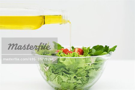 Olive oil being poured onto salad, close-up