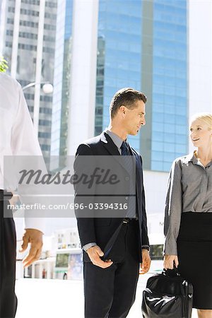Two business associates standing on sidewalk, looking at each other, discussing