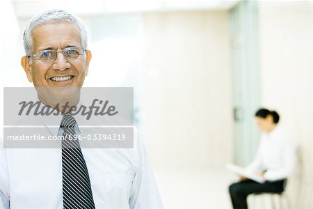 Mature businessman smiling at camera, head and shoulders, portrait