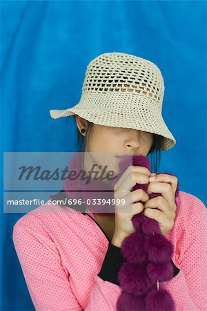 Teenage girl with hat covering eyes, holding boa, portrait
