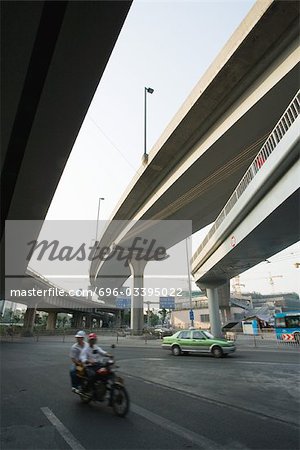 Motorcycle and taxi driving under overpasses