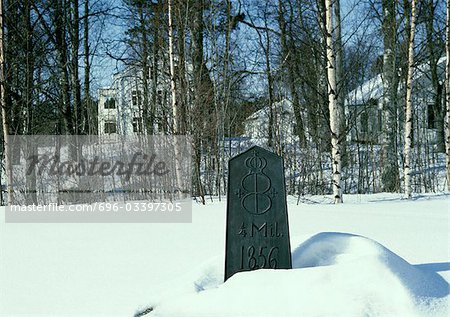 Sweden, marker in snow, houses in woods in background