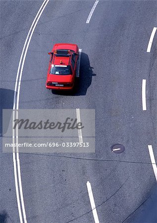 Red car on road with white lines, high angle view, full frame