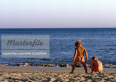 Nude children playing on beach, rear view