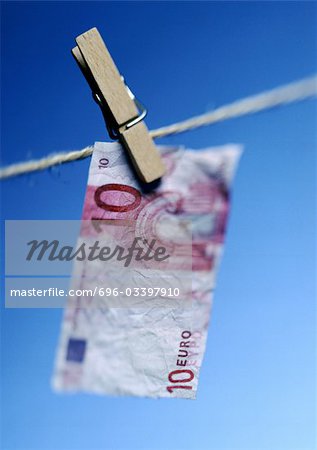 Ten euro bill hanging on clothesline with clothes peg, close-up.