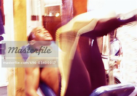 Man using weight machine in gym, blurred motion
