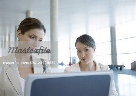 Two women looking at screen in airport