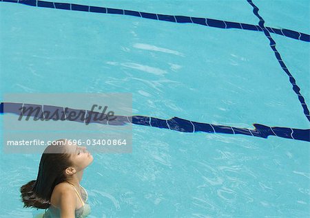 Woman standing in pool with head back and eyes closed