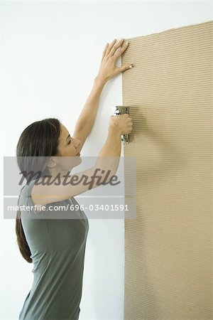 Woman stapling sheet of cardboard to wall