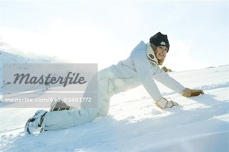 Teenage girl down on all fours in snow, smiling at camera