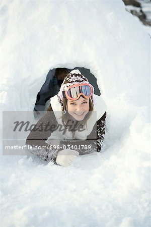 Teen girl crawling out of tunnel in snow