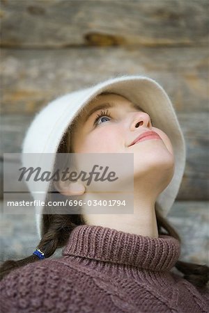 Teenage girl wearing hat, looking up, portrait