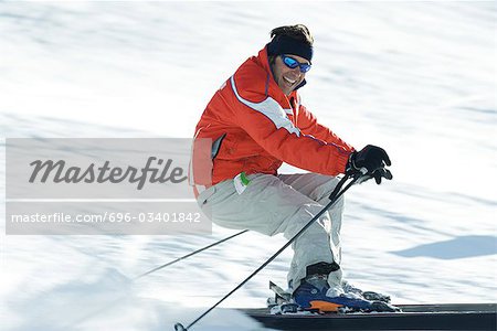 Mature male skier on ski slope, smiling toward camera, blurred motion