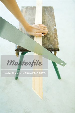 Woman sawing wood with saw, cropped view of hand