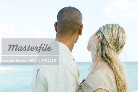 Couple looking at ocean view together, rear view