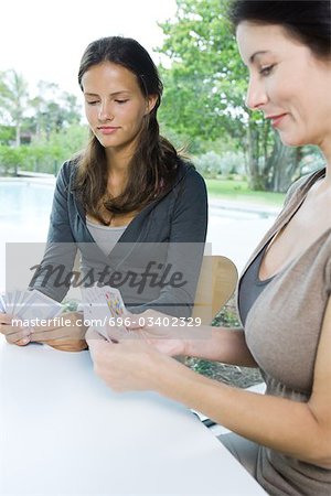 Mother and daughter playing cards together, both looking down