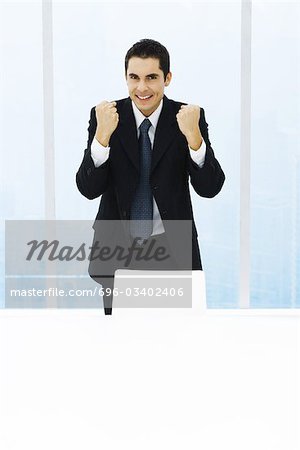 Businessman standing with fists up, smiling at camera