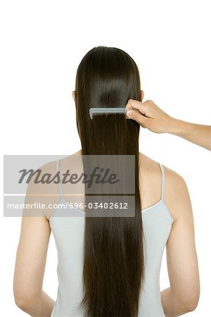 Woman having her long hair combed, rear view