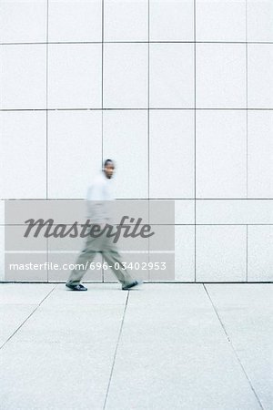 Man walking with hands in his pockets down sidewalk