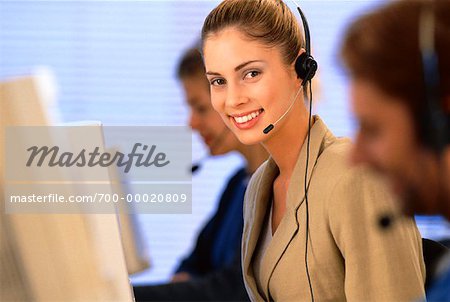Portrait of Businesswoman Sitting At Computer, Using Telephone Headset