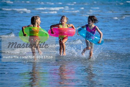 Girls in Swimwear, Running on Beach with Inner Tubes