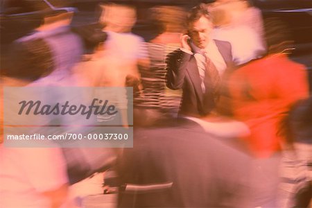 Businessman Using Cell Phone In Crowd