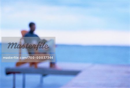 Blurred View of Man Sitting in Chair on Dock
